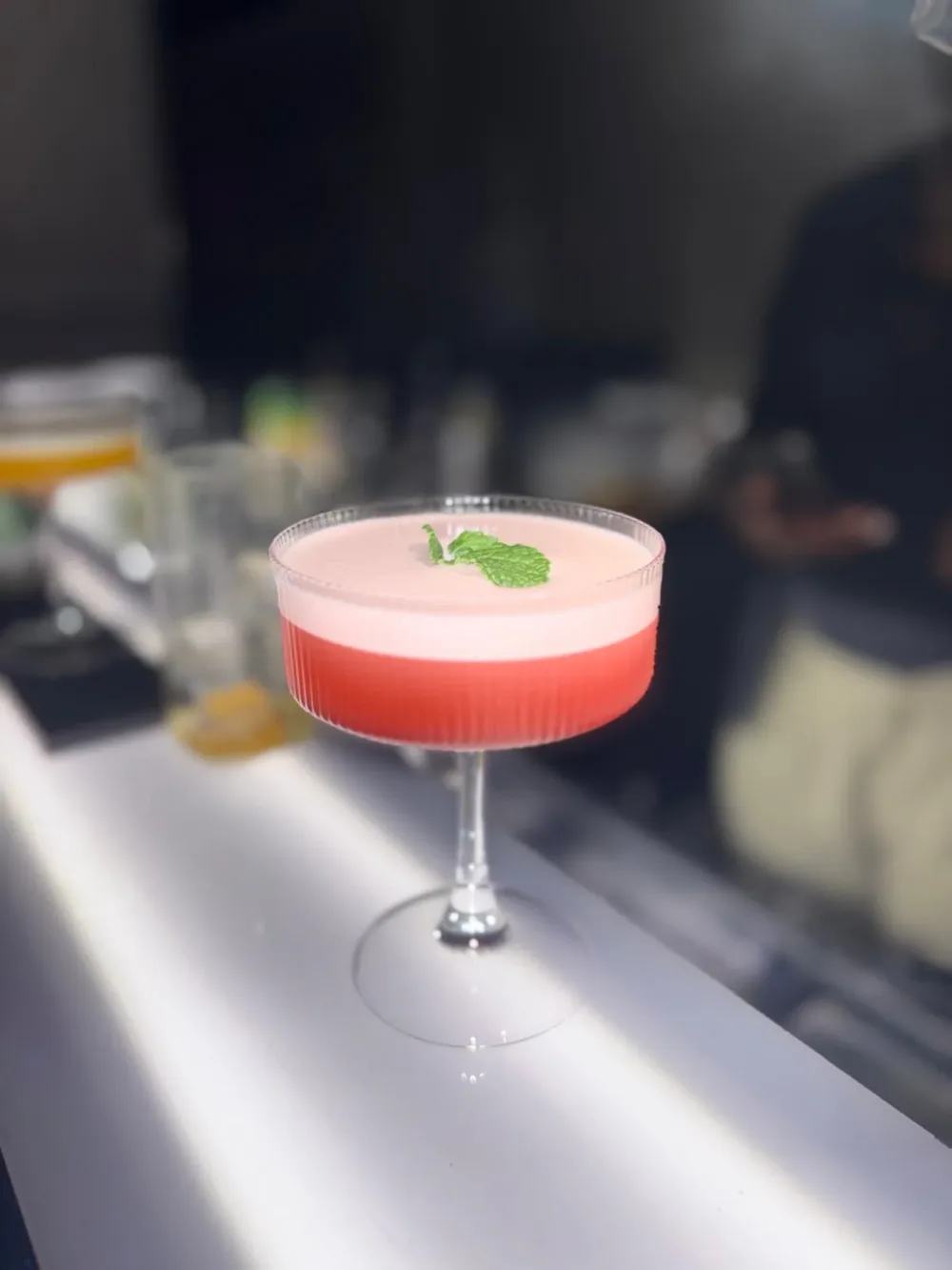 Cocktail rose à la mousse délicate dans un verre à pied.